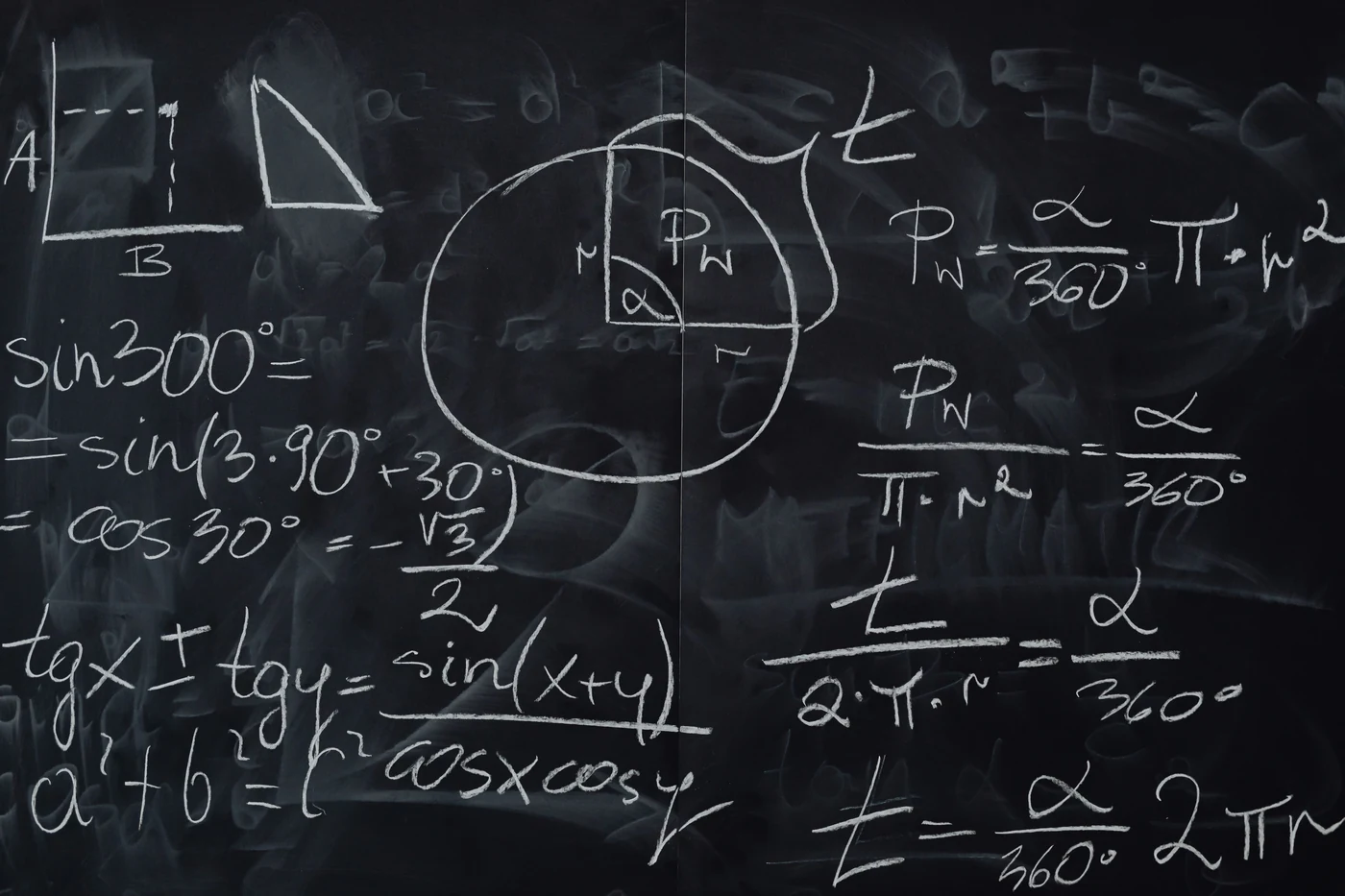 A blackboard covered in handwritten chalk working: trigonometric identities, a circle with an inscribed angle and radius marked, and the Pythagorean theorem.